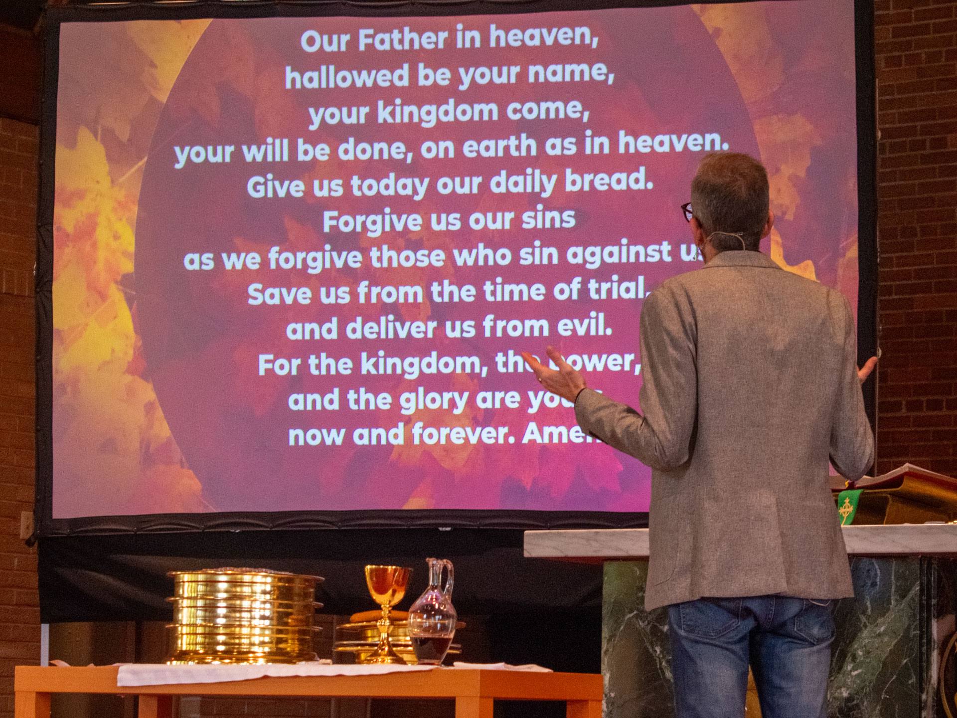 Pastor leading the Lord's Prayer during worship